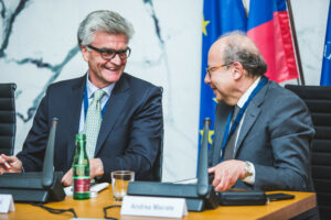 Two panellists look at each other and smile. EU flag is in the background